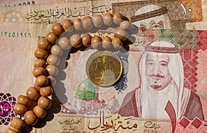 Top view of money, banknote and coin of Saudi Arabia Riyals and prayer beads, in shallow focus