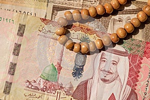 Top view of money or banknote of Saudi Arabia Riyals and prayer beads, in shallow focus