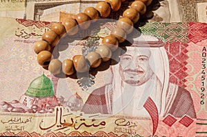 Top view of money, banknote of Saudi Arabia Riyals and prayer beads, in shallow focus