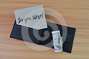 Top view of money banknote, wallet and memo note written with SEE YOU THERE