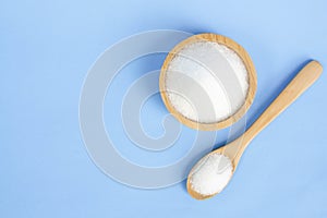 Top view monosodium glutamate in wood bowl and spoon on light bl