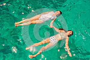 Top view of mother and daughter enjoying summer at blue caves in Zakynthos island in Greece wearing the same swimsuit.