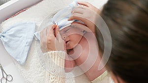 Top view of mother dressing her newborn baby son in bodysuit lying on changing table. Concept of babies and newborn