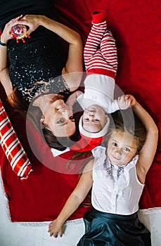 Top view of mother and her little two children lying on carpet on the eve of Christmas. Closeup