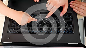 Top view of mother and little son pressing buttons on laptop keyboard. Child learning using computers and laptops