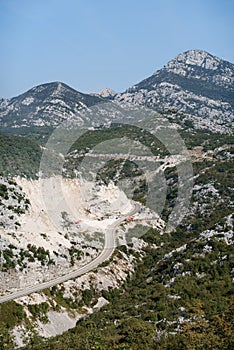 Top view of a mountain serpentine road on a mountain wasteland with green trees and mountain views.