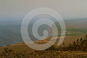 top view from the mountain shore of lake Baikal in fog, smoke, after fire