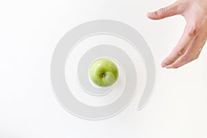 Top view of Moving left hand for grabbing a green apple on white background