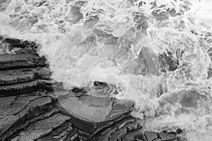 Top view on moving sea water against rocks with waves and foam, texture background pattern in black and white