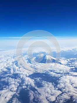 Top view - Mt Fuji from sky view on window seat of plane. Blue sky and many clouds