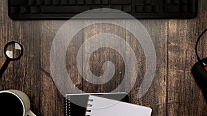 Top View of mug of strong coffee , copybooks, computer keyboard and other stationery on dark wooden backdrop