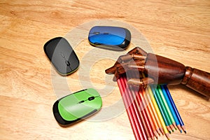 Top view of multi-colored pencils, computer mouses with an articulated wooden hand