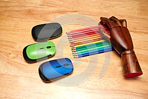 Top view of multi-colored pencils, computer mouses with an articulated wooden hand