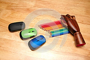 Top view of multi-colored pencils, computer mouses with an articulated wooden hand