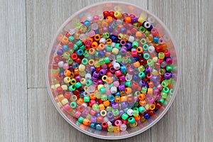 Top view of multi-colored plastic beads on plastic container in a table