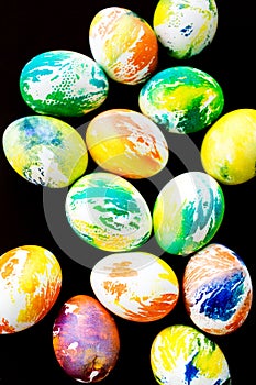 Top view multicolored eggs on a black isolated background. Happy Easter card