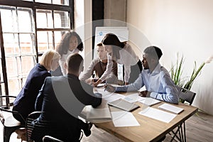 Diverse employees discuss business paperwork at meeting photo