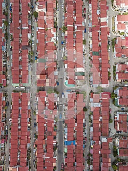 Top view of multiple blocks of townhouses with red steel roofs and narrow streets. A crowded subdivision in Imus, Cavite.