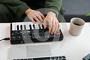 Top view of music producer or arranger using laptop and midi keyboard and other audio equipment to create music at home