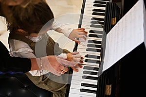 Top view music teacher, pianist holding the hands of a child girl, teaching piano lesson showing correct finger position