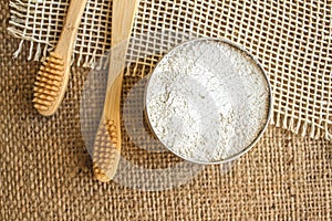 Top view on natural bamboo toothbrushes and kaolin dentifrice on rustic burlap background with copy space. Sustainable lifestyle photo