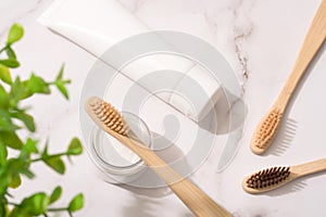Top view on natural bamboo toothbrushes, mineral toothpowder and toothpaste tube on white table