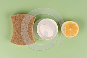 Top view on natural household cleaners kit -  organic dishcloth, lemon, baking soda, citric acid on light green background