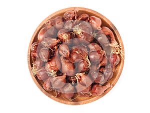 Top view of natural organic fresh raw red shallot onion on round wooden plate isolated on white background.