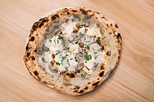 Top view of Neapolitan pizza: Stir-fried Swiss mushrooms topped with special truffle sauce pizza, Served on a white plate.