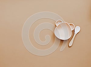 Top view neutral baby tableware on brown background,