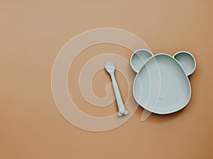 Top view neutral baby tableware on brown background