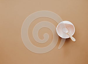 Top view neutral baby tableware on brown background, flat lay ,