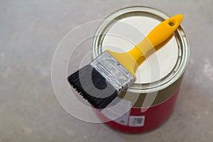 Top view of new shiny clean sealed tin full of red paint and painting brush on it, on white. Tools, materials, building a