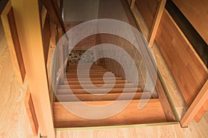 Top view of a new wooden staircase with railing lit by a window