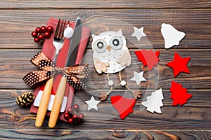 Top view of New Year dinner on wooden background. Festive cutlery on napkin with christmas decorations and toys. Close up of