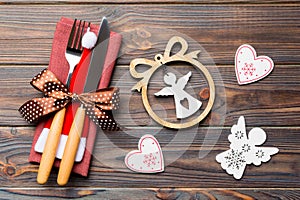 Top view of New Year dinner on wooden background. Festive cutlery on napkin with christmas decorations and toys. Close up of