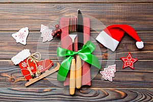 Top view of New Year dinner on wooden background. Festive cutlery on napkin with christmas decorations and toys. Close up of