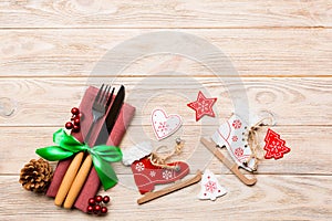 Top view of New Year dinner on wooden background. Festive cutlery on napkin with christmas decorations and toys. Family holiday