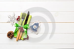 Top view of New Year dinner on wooden background. Festive cutlery on napkin with christmas decorations and toys. Family holiday