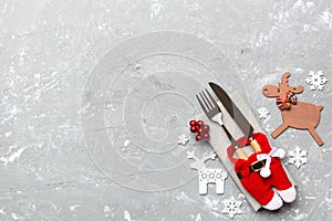 Top view of new year utensils on napkin with holiday decorations and reindeer on cement background. Christmas dinner concept with