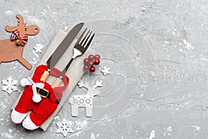 Top view of new year utensils on napkin with holiday decorations and reindeer on cement background. Christmas dinner concept with