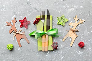Top view of new year utensils on napkin with holiday decorations and reindeer on cement background. Close up of Christmas dinner