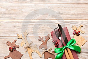 Top view of new year utensils on napkin with holiday decorations and reindeer on wooden background. Christmas dinner concept with