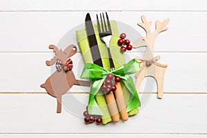 Top view of new year utensils on napkin with holiday decorations and reindeer on wooden background. Christmas dinner concept with