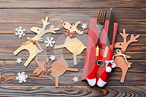 Top view of new year utensils on napkin with holiday decorations and reindeer on wooden background. Close up of christmas dinner