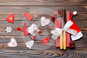 Top view of new year utensils on napkin with holiday decorations and reindeer on wooden background. Close up of christmas dinner