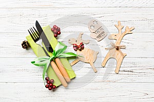 Top view of new year utensils on napkin with holiday decorations and reindeer on wooden background. Close up of christmas dinner