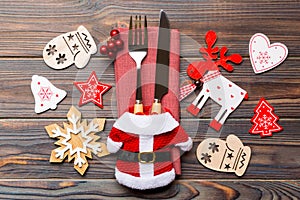 Top view of new year utensils on napkin with holiday decorations and reindeer on wooden background. Close up of christmas dinner