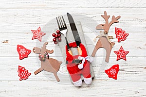 Top view of new year utensils on napkin with holiday decorations and reindeer on wooden background. Close up of christmas dinner