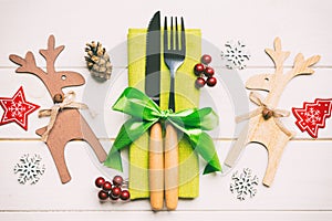 Top view of new year utensils on napkin with holiday decorations and reindeer on wooden background. Close up of christmas dinner